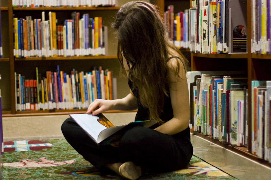 Девушки читают текст. Девушка с книгой. Брюнетка с книжкой. Чтение книг. Девушка в библиотеке.